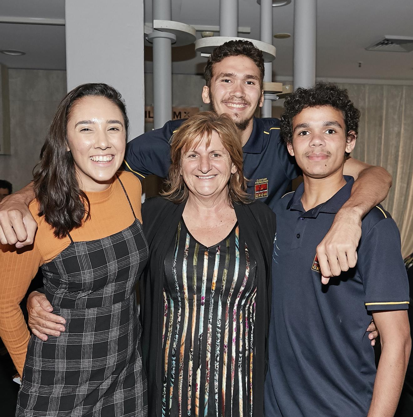 Four Indigenous people in a group photo. The central figure is CUA Elder-in-Residence Aunty Glendra Stubbs. To her right is a female Indigenous student, to her left and behind her are two young Indigenous high school students.