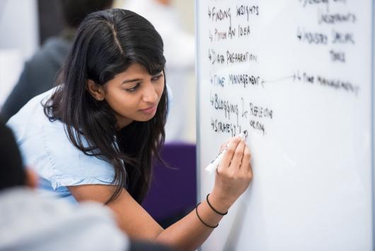 CUA student writing on a white board