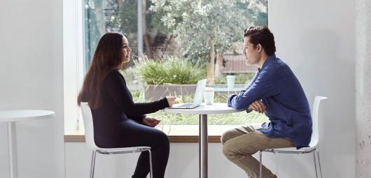 man and woman interview at a desk by the window