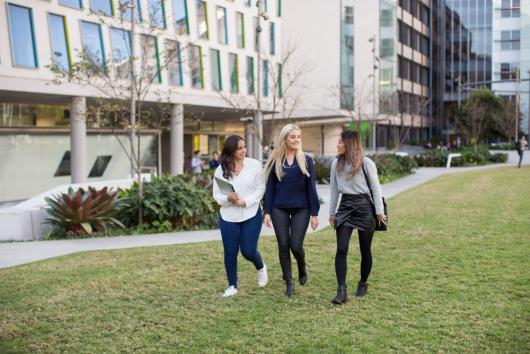 CUA students walking on the grass in front of Graduate School of Health