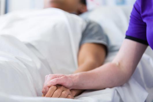 CUA nurse holding a patients hand