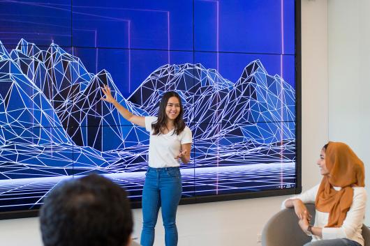 Students discussing 3D map on a large screen