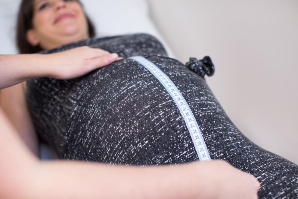 Pregnant ladies bump being measured with a tape measure