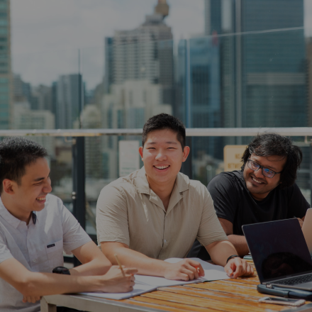 Three guys sitting on table laughing with skyline as the backdrop