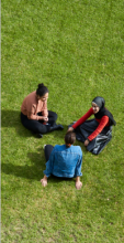 Three CUA students sitting together outside at alumni green