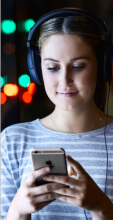 CUA student wearing headphones and engaged with her mobile phone