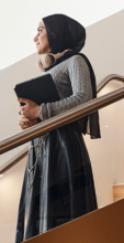 CUA persona carrying laptop while walking down the staircase on campus